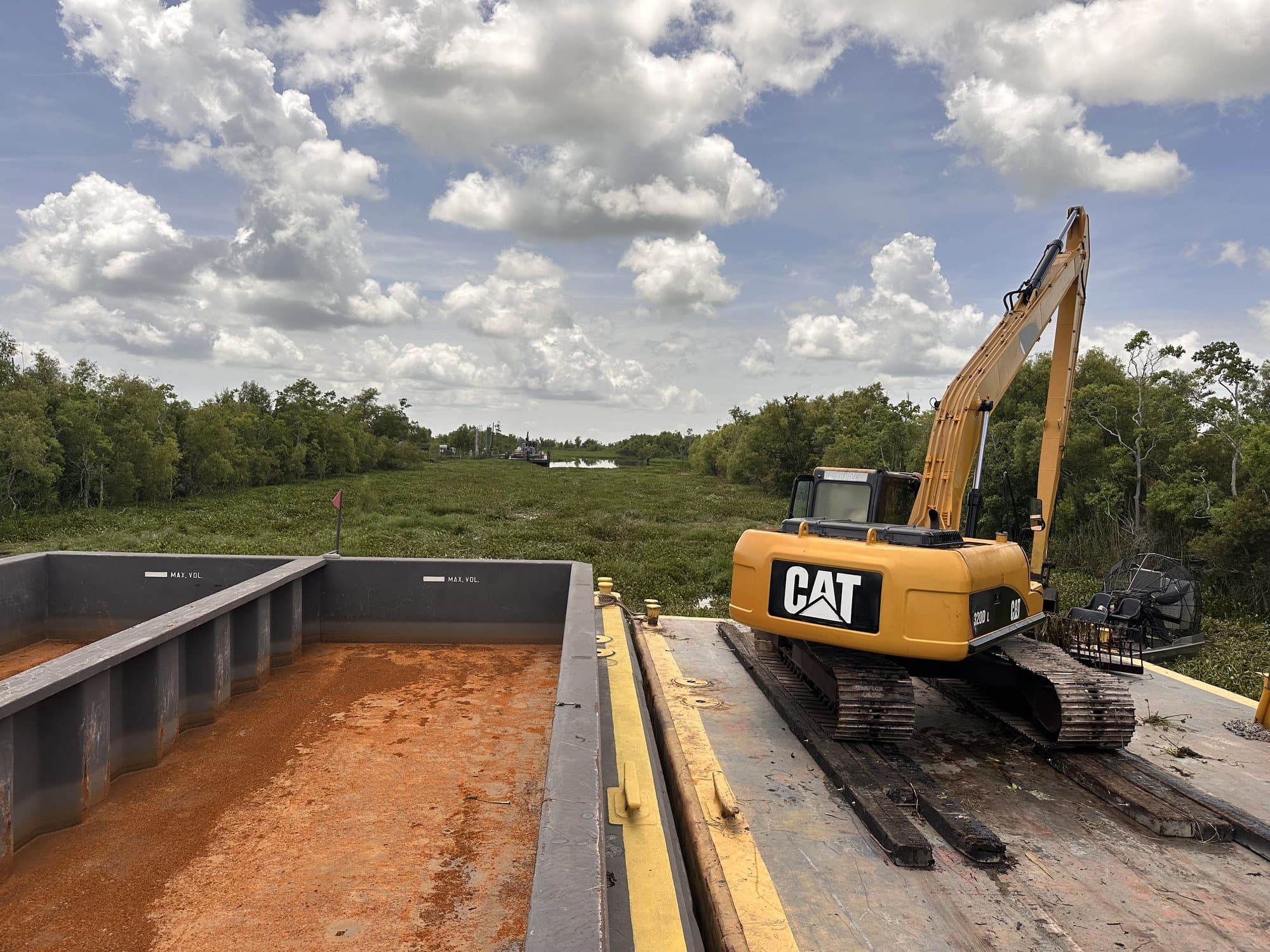 Excavator loading a hopper barge from a spud barge in South Louisiana